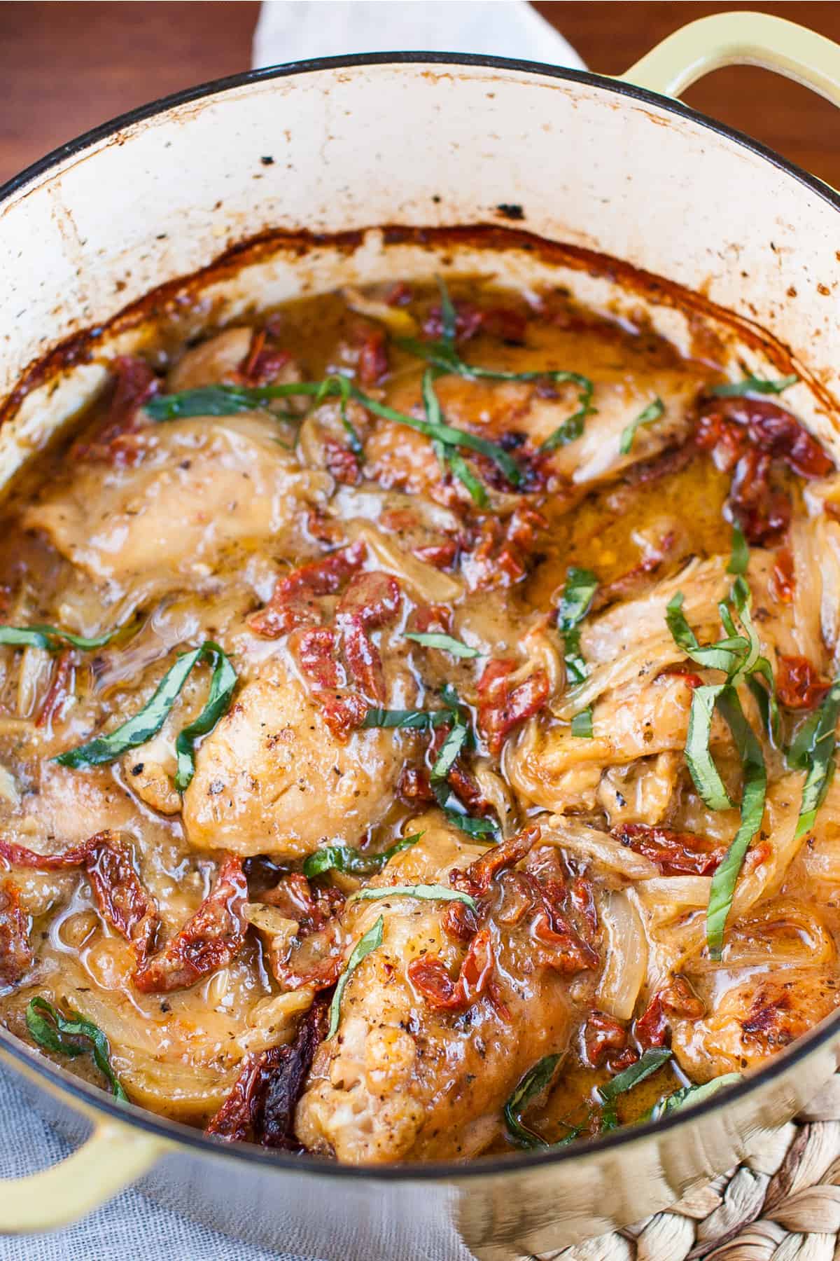 Creamy sun-dried tomato chicken in a pot with basil on top.
